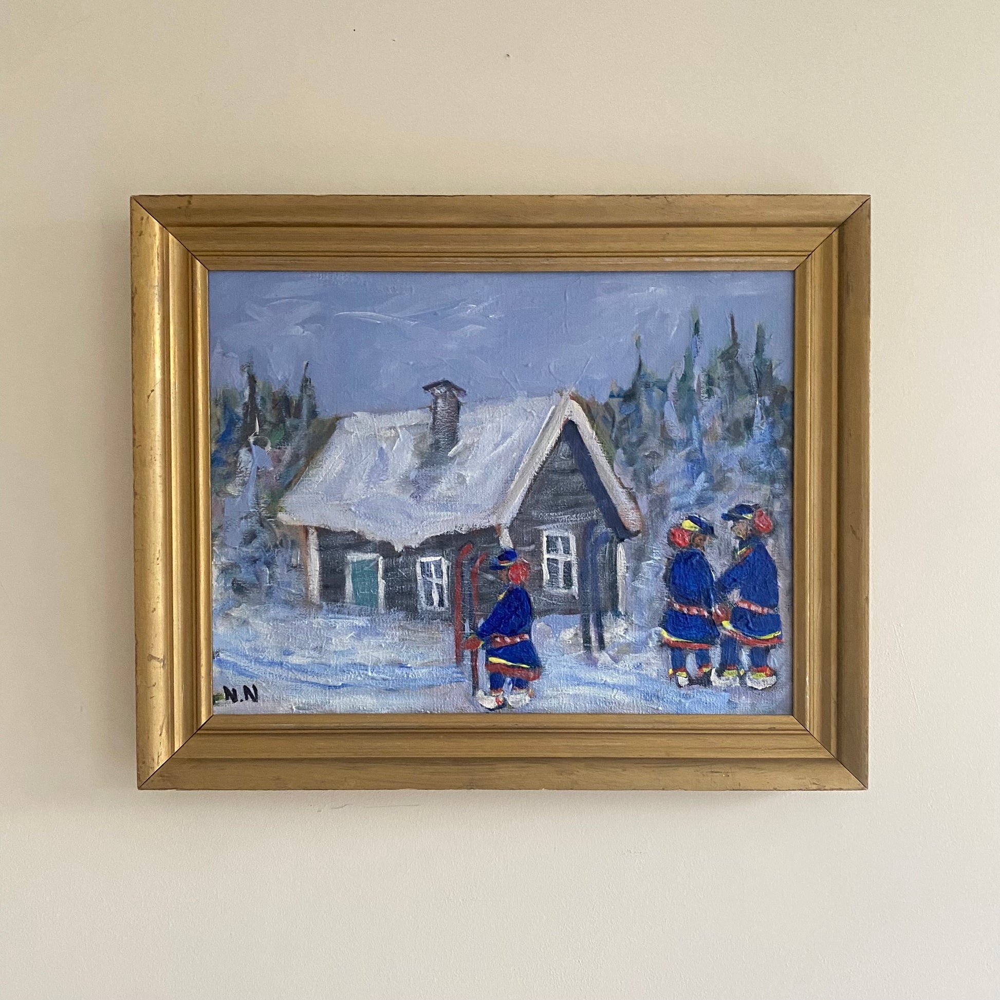 
A framed painting depicting a snowy village scene. The artwork shows a woman pushing a baby stroller along an icy road, a dog trotting nearby, and a person riding a bicycle in the distance. Snow covers the houses, fences, and trees, creating a serene winter atmosphere. The