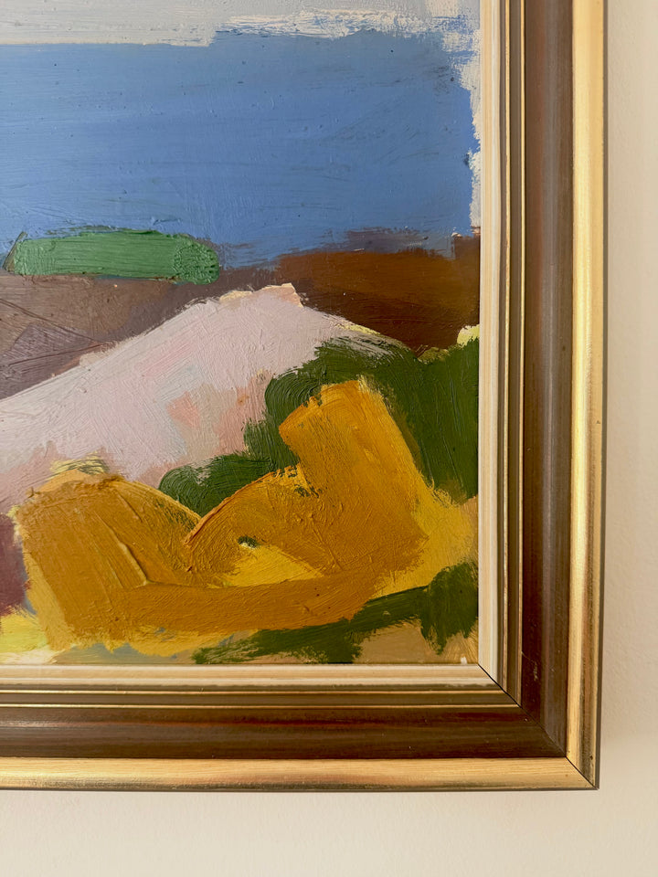 Close-up of an abstract landscape painting in a gold-toned frame, showing blue sky, green hills, brown land, and a pale pink foreground with yellow brushstrokes.