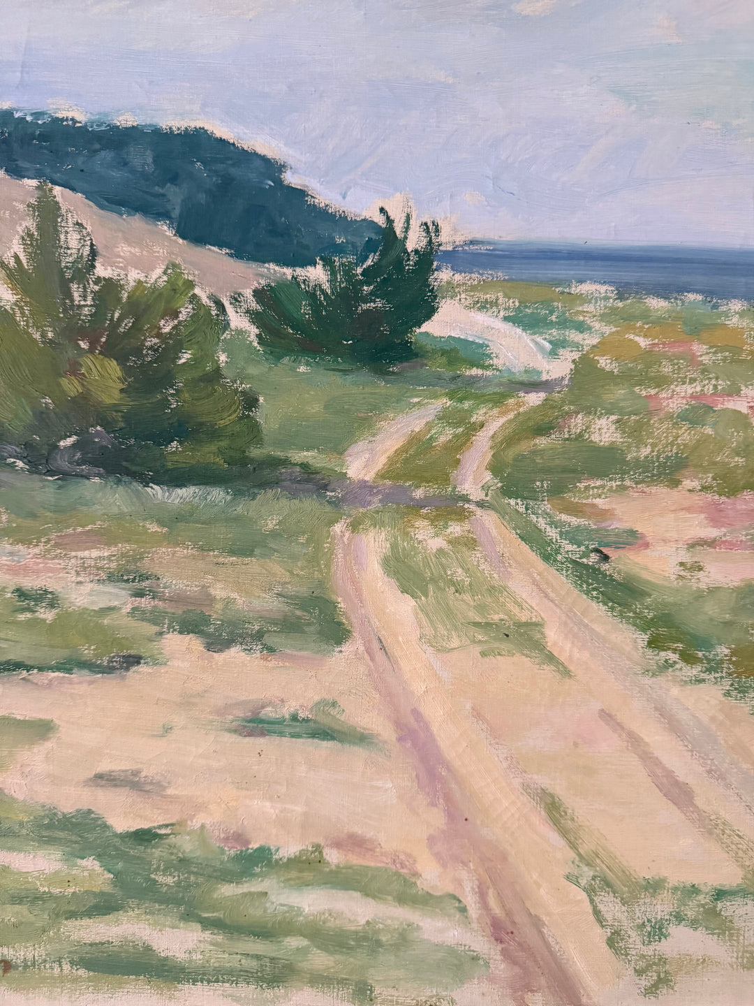 Impressionist landscape painting of a winding dirt path leading through green grassy fields toward a coastal ocean scene under a pale sky.