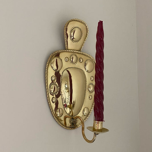 Vintage Swedish mid-century brass wall sconce for candle shown with red candle